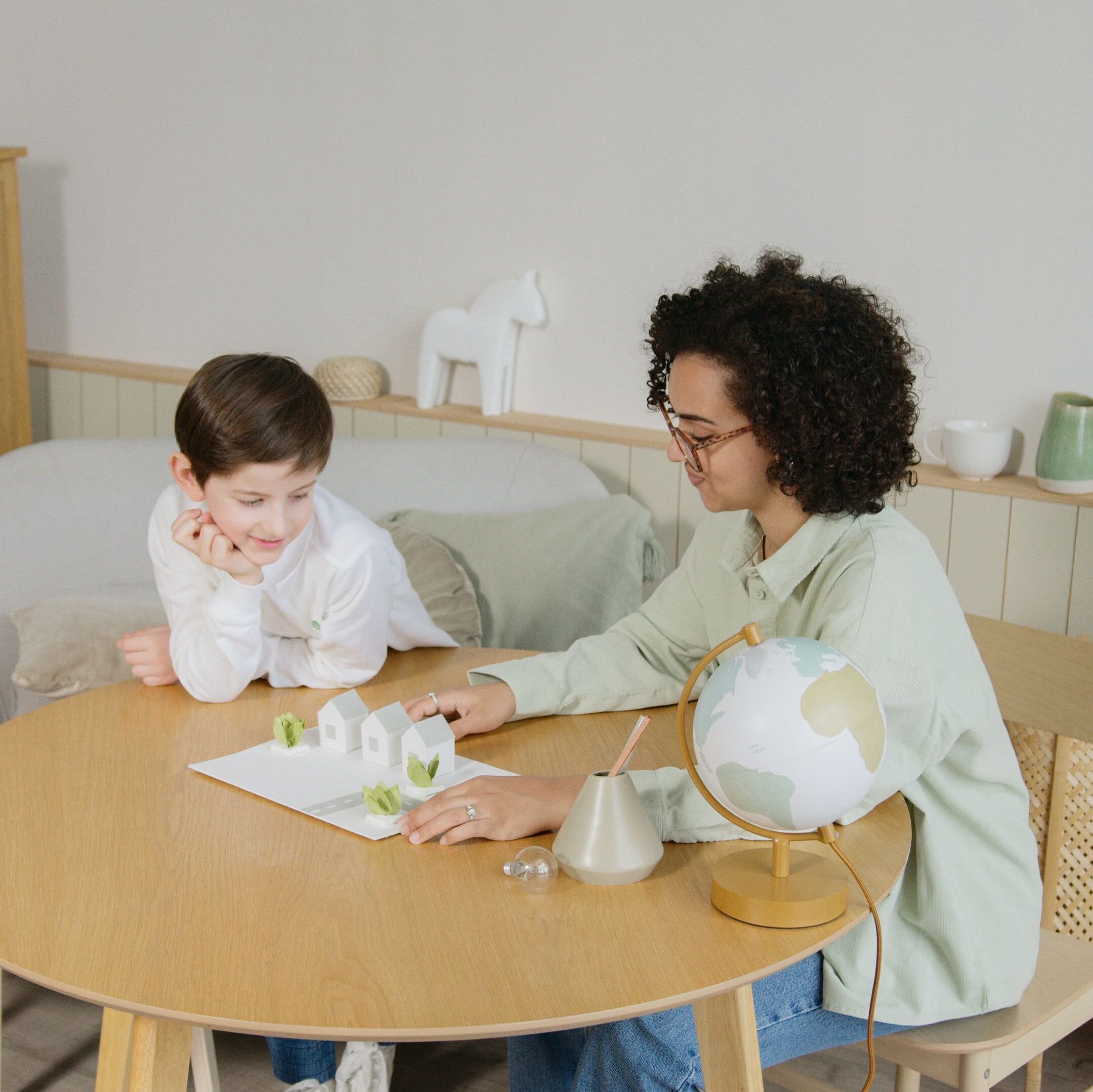 Mamá y su bebé de 18 meses sentados en una mesa de trabajo infantil, manipulando un juguete educativo en Centro Conecta - Dos.